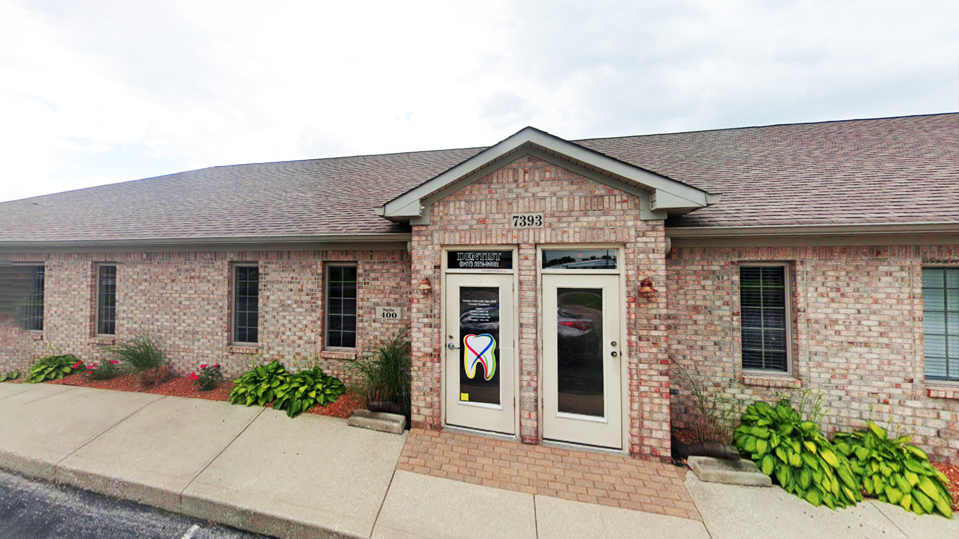The image shows a building with a brick facade and a white roof, featuring a prominent entrance.